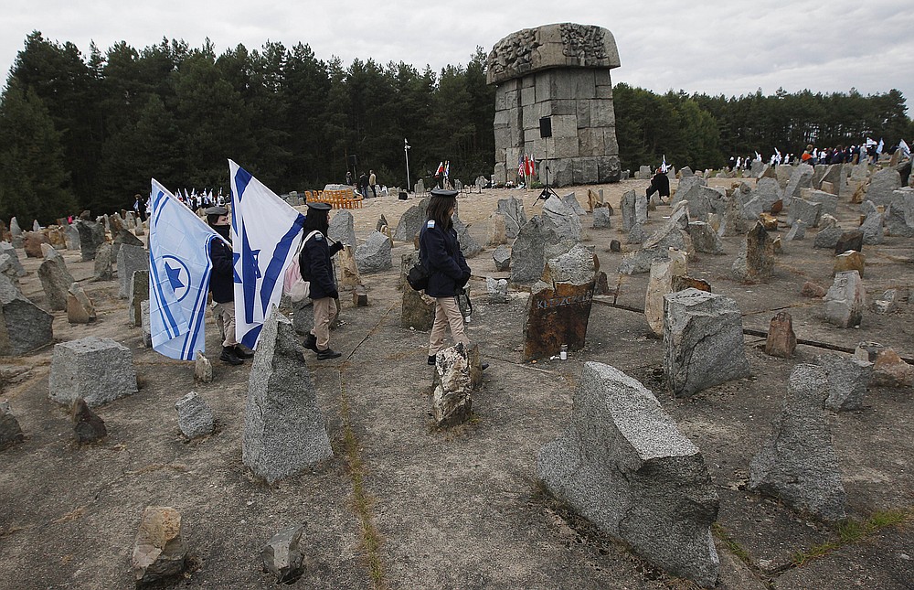 PLIK _ Na tym pliku zdjęcie ze środy, 2 października 2013 r., Izraelska młodzież maszeruje ze swoimi flagami narodowymi obok pomnika około 900 000 europejskich Żydów, którzy zostali zabici przez nazistów w latach 1941-1944 w obozie zagłady i pracy w Treblince przy pomniku w Treblince .  Polska.  Dwóch polskich historyków stoi w obliczu pomówienia za naukowe badanie polskiego zachowania podczas II wojny światowej.  Ten przypadek może przesądzić o losach niezależnych badań nad Holokaustem pod nacjonalistycznym rządem Polski.  Werdykt spodziewany jest 9 lutego.  (AP Photo / Czarek Sokolowski, File)