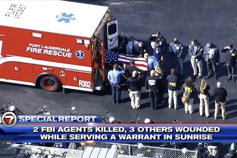 Law enforcement officers load a casket into a vehicle, Tuesday, Feb. 2, 2021, in Sunrise, Fla. Two FBI agents were fatally shot and three wounded while trying to serve a search warrant in Florida on Tuesday, prompting a SWAT team to storm an apartment building where the suspect was holed up as neighbors huddled inside their homes. (WSVN-TV via AP)