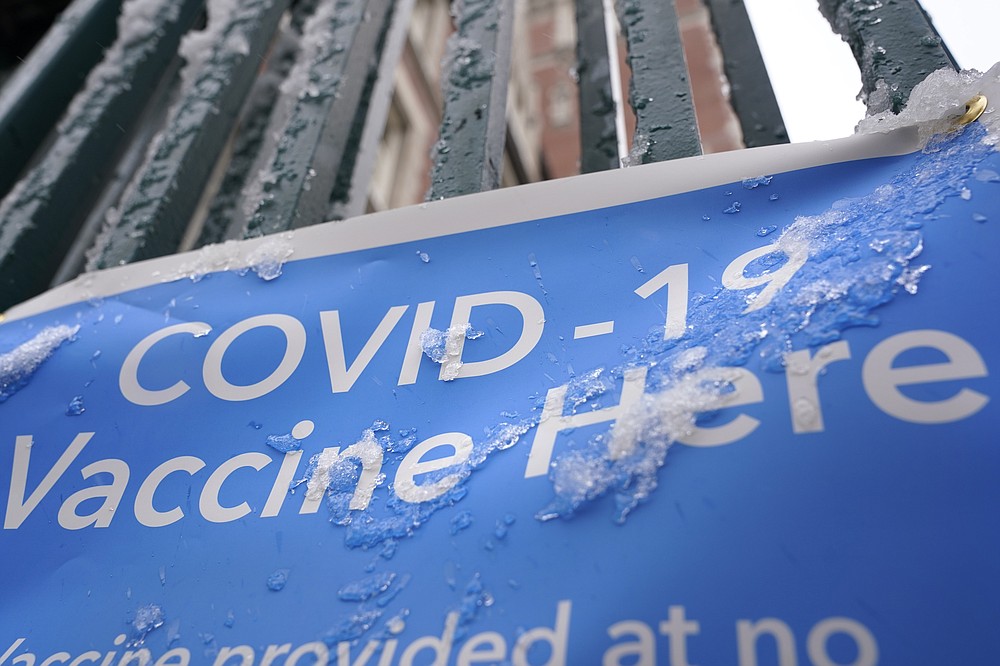 A sign covered with ice advertises a COVID-19 vaccination site in New York, Tuesday, Feb. 2, 2021. The site was closed today due to the inclement weather. Coronavirus vaccination sites across the Northeastern U.S. are getting back up and running after a two-day snowstorm that also shut down public transport, closed schools and canceled flights. Some vaccination sites in New York City remained closed, but others, including those run by the public hospital system, were open Tuesday. (AP Photo/Seth Wenig)