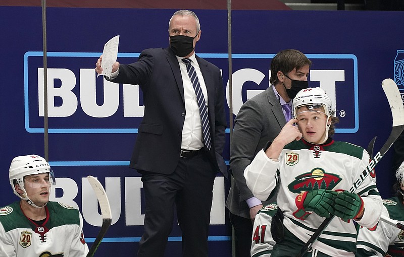 Minnesota Wild coach Dean Evason, back, directs the team during the third period of an NHL hockey game against the Colorado Avalanche on Tuesday, Feb. 2, 2021, in Denver. (AP Photo/David Zalubowski)