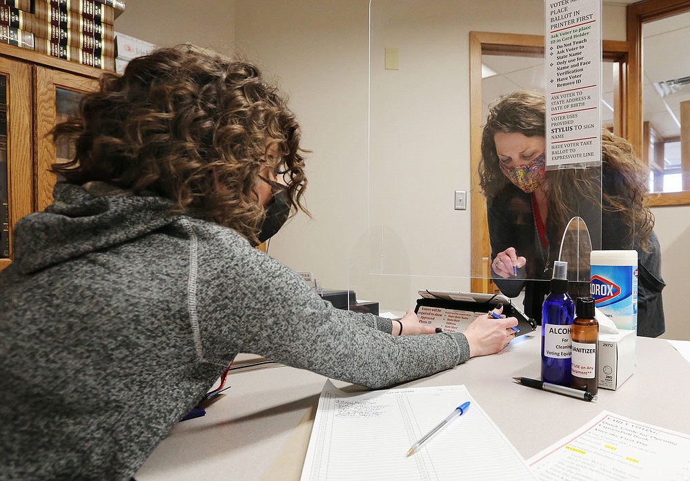 Roxi Reed (right), of Prairie Grove, is assisted by Rochelle Caswell, deputy county clerk, Friday as she picks up her ballot to vote early at the Washington County Courthouse in Fayetteville. Early voting for the Farmington School District and Prairie Grove special elections ends Monday. Early votes can be cast from 8 a.m. to 4:30 p.m. in the Quorum Court meeting room in the Washington County Courthouse, 280 N. College Ave. in Fayetteville. Check out nwaonline.com/210206Daily/ and nwadg.com/photos for a photo gallery.
(NWA Democrat-Gazette/David Gottschalk)