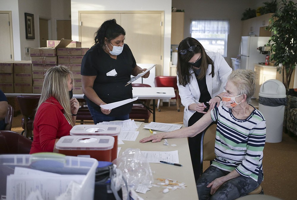 Nurse Brenna Neumann (third from left) administers a covid-19 vaccine to Gail Cawsey (right) as Tracy Schnick (from left) and Mary Avila process vaccine recipients, Friday, February 5, 2021 at Apple blossom retirement community in Rogers. Forty residents at Apple Blossom retirement community received their covid-19 vaccines. Check out nwaonline.com/210206Daily/ for today's photo gallery.
(NWA Democrat-Gazette/Charlie Kaijo)