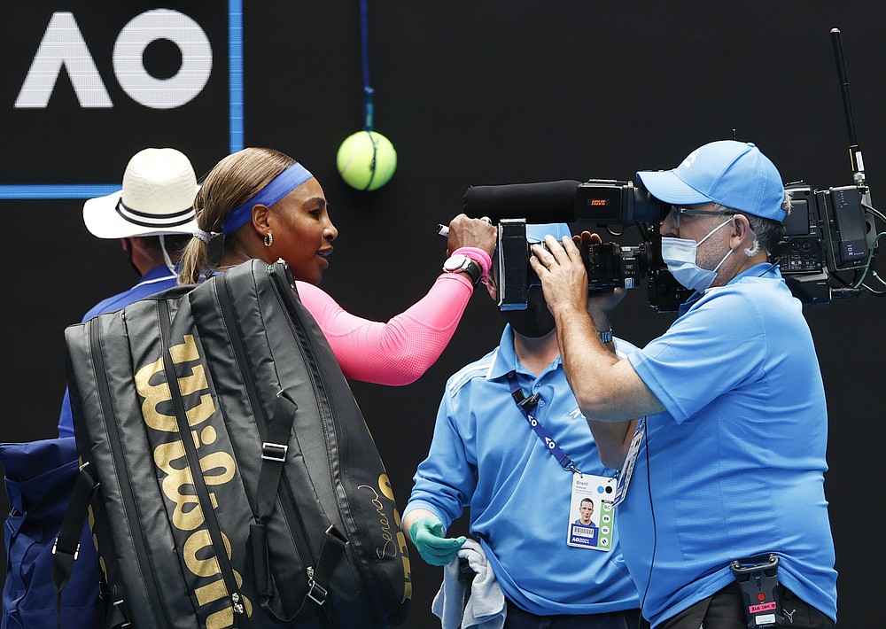 United States' Serena Williams signs the TV camera lens after defeating Germany's Laura Siegemund during their first round match at the Australian Open tennis championship in Melbourne, Australia, Monday, Feb. 8, 2021.(AP Photo/Rick Rycroft)