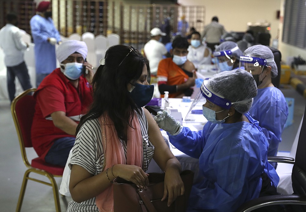A woman receives a Sinopharm COVID-19 vaccine from a medical staffer at the Guru Nanak Darbar Sikh Temple, in Dubai, United Arab Emirates, Monday, Feb. 8, 2021. With the coronavirus pandemic surging to new heights in the UAE, the Sikhs of Dubai have traded their traditional fare of free meals for free COVID-19 vaccines. The city's Sikh temple is administering 5,000 shots to those who may otherwise struggle to be vaccinated. (AP Photo/Kamran Jebreili)