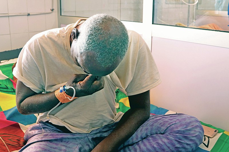 Ousseni Yanogo, 63, sits on his bed at Ouagadougou's Bogodogo Medical Teaching Hospital Thursday Feb. 4, 2021. Yanogo contracted COVID-19 at his 6-year-old grand-daughter's birthday. Since November, the conflict-riddled West African nation of Burkina Faso faces a much deadlier second coronavirus wave than the first and health officials worry a lack of knowledge and adherence to coronavirus measures is making it hard to rein in. (AP Photo/Sam Mednick)