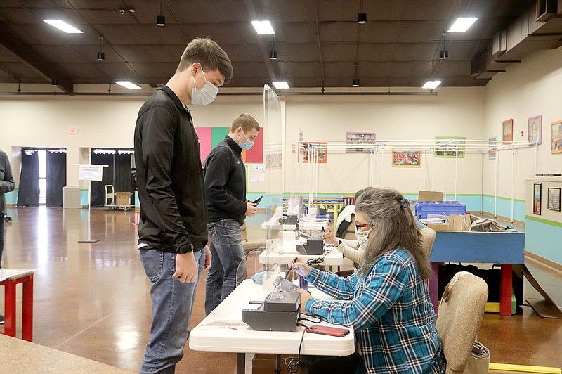 LYNN KUTTER ENTERPRISE-LEADER
Prairie Grove High seniors Blake Gardner, left, and Knox Laird prepare to receive their ballots for the Feb. 8 special election in Prairie Grove. Election official Peggy Hatfield is assisting Gardner. City voters approved all nine questions on the election ballot.
