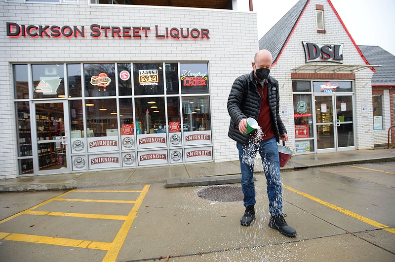 Billy Waite, the owner of Dickson Street Liquor, spreads salt Wednesday outside the business as he opens for the day on Dickson Street in Fayetteville. Wintry weather and freezing temperatures are expected to continue into next week. Visit nwaonline.com/210211Daily/ for today's photo gallery. 
(NWA Democrat-Gazette/Andy Shupe)