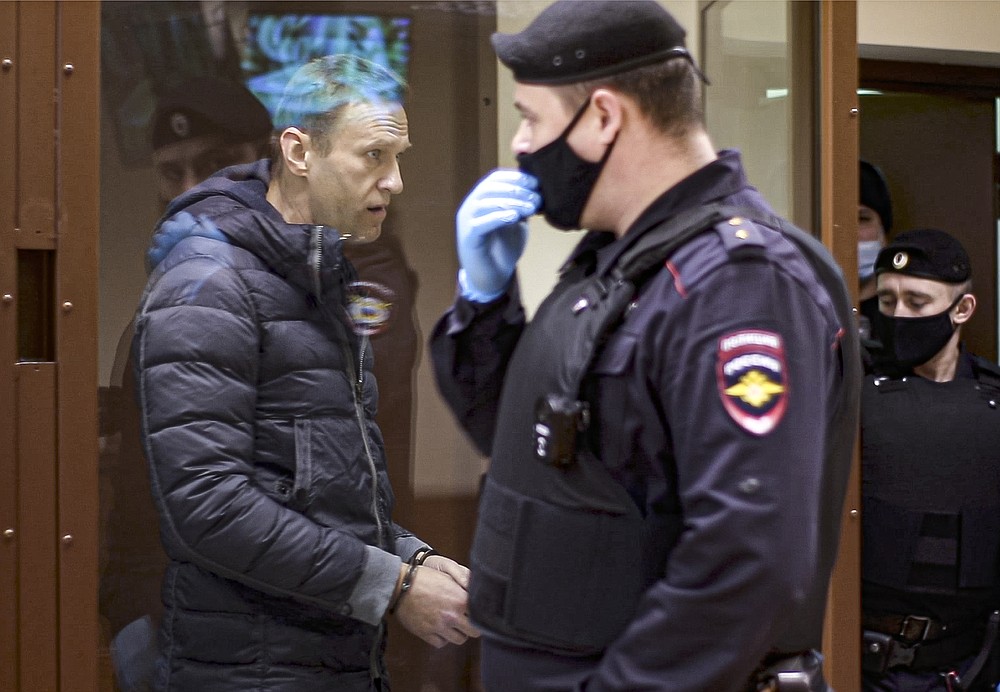 In this photo taken taken from a footage provided by the Babuskinsky District Court on Friday, Feb. 12, 2021, Russian opposition leader Alexei Navalny, left, enters a cage to attend a hearing on charges of defamation in the Babuskinsky District Court in Moscow, Russia. Navalny was accused of slandering a World War II veteran featured in the video promoting the constitutional reform allowing to extend President Vladimir Putin's rule. The politician slammed people in the video as "traitors" and stands trial on defamation charges. (Babuskinsky District Court Press Service via AP)