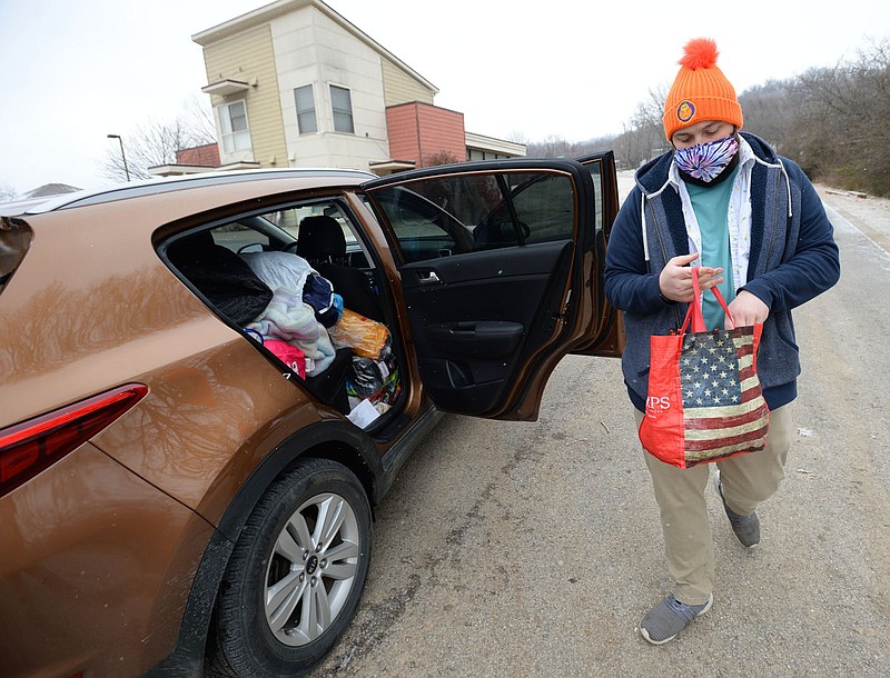 Ryan Tinsley, vice president and homeless outreach coordinator for MayDay Community Kitchen, hands out food, blankets, hand warmers, tents, gloves and other cold weather gear Friday, Feb. 12, 2021, at the Safe Camp community in south Fayetteville. 7 Hills Homeless Center, which oversees Safe Camp, was allocated $50,0000 from Fayetteville√¢‚Ç¨‚Ñ¢s Community Development Block Grant program to operate a cold weather response for people experiencing homelessness. Visit nwaonline.com/210214Daily/ for today's photo gallery. 
(NWA Democrat-Gazette/Andy Shupe)