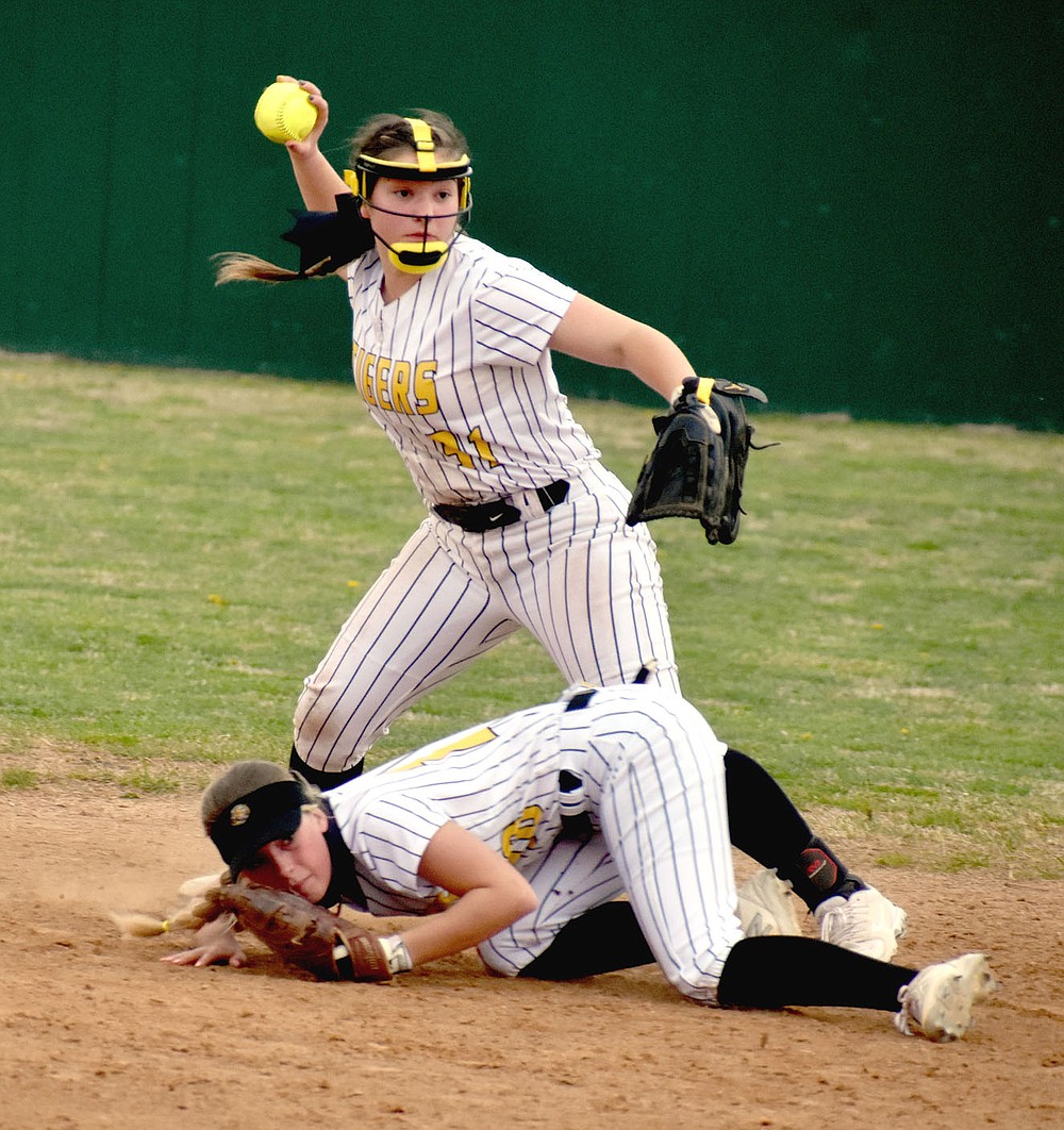 MARK HUMPHREY ENTERPRISE-LEADER/Picture perfect teamwork. Prairie Grove senior shortstop Makinsey Parnell comes to the aid of classmate Sydney Stearman, who dove on the ground to stop a hit in the infield, but couldn't get up in time to make the throw to first. Parnell took care of that chore, recording the third out to give the Lady Tigers a chance trailing 5-2 coming into their last at-bat and win 6-5 with four runs crossing the plate in the bottom of the seventh against Berryville.