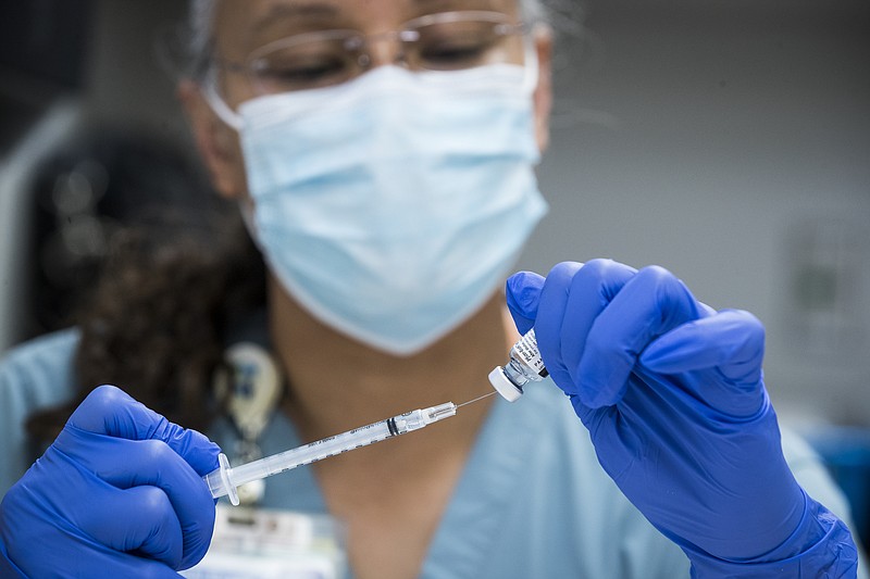 FILE - In this Thursday, Feb. 11, 2021 file photo, pharmacy technician Sochi Evans fills a syringe with a Pfizer-BioNTech COVID-19 vaccine at Texas Southern University in Houston. Coronavirus cases are continuing to decline in the U.S. after a winter surge. Researchers at Johns Hopkins University say the seven-day average of new coronavirus cases in the country dropped below 100,000 on Friday, Feb. 12 for the first time since November 4. (Brett Coomer/Houston Chronicle via AP, File)