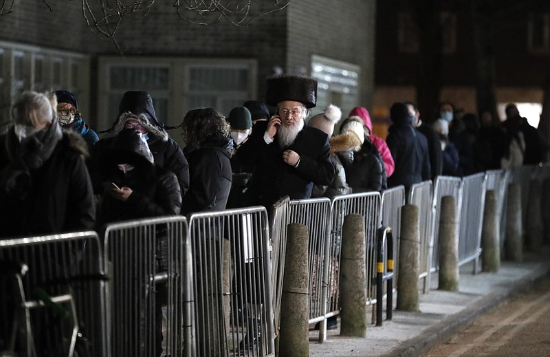 A man from the Haredi Orthodox Jewish community, center, queues outside an event to encourage vaccine uptake in Britain's Haredi community at the John Scott Vaccination Centre in London, Saturday, Feb. 13, 2021. The event aims to breakdown some of the misconceptions about vaccines, as well as myths and negative publicity surrounding the Haredi community which has been hard hit during the COVID-19 pandemic. (AP Photo/Frank Augstein)