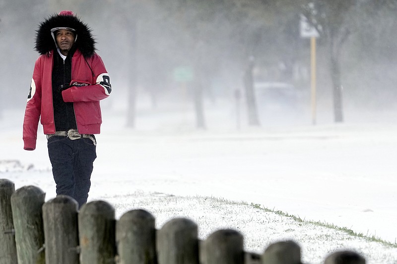 Igee Cummings walks through the snow Monday, Feb. 15, 2021, in Houston. A winter storm dropping snow and ice sent temperatures plunging across the southern Plains, prompting a power emergency in Texas a day after conditions canceled flights and impacted traffic across large swaths of the U.S. (AP Photo/David J. Phillip)