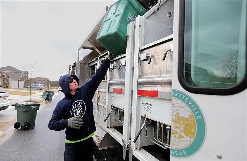 Christopher Webb, with the city of Fayetteville's Recycling and Trash Collection Division, empties the last contest of a recycling bin March 19 in the Park Meadows area of Fayetteville. The city pushed recycling and trash service because of inclement weather this week. (File photo/NWA Democrat-Gazette/David Gottschalk)