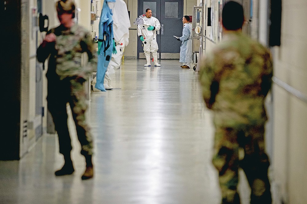 FILE - In this March 19, 2020 file photo, biological science specialists, background, wear biosafety protective clothing for handling viral diseases at U.S. Army Medical Research and Development Command at Fort Detrick in Frederick, Md. On March 9, 2020, a public WeChat account called "Happy Reading List" reposted an essay claiming the U.S. military created SARS-CoV-2, the virus that causes COVID-19, at a lab in Fort Detrick and loosed it in China during the Military World Games, an international competition for military athletes, held in Wuhan in October 2019. (AP Photo/Andrew Harnik)