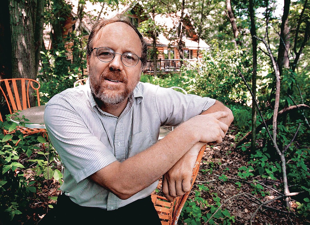 FILE - In this July 6, 2006 file photo, University of Wisconsin-Madison lecturer Kevin Barrett sits outside his cabin in Lone Rock, Wis. Barrett said he is "80%" sure coronavirus was created by the U.S. as a bioweapon and used to attack China. (Mike DeVries/The Capital Times via AP)