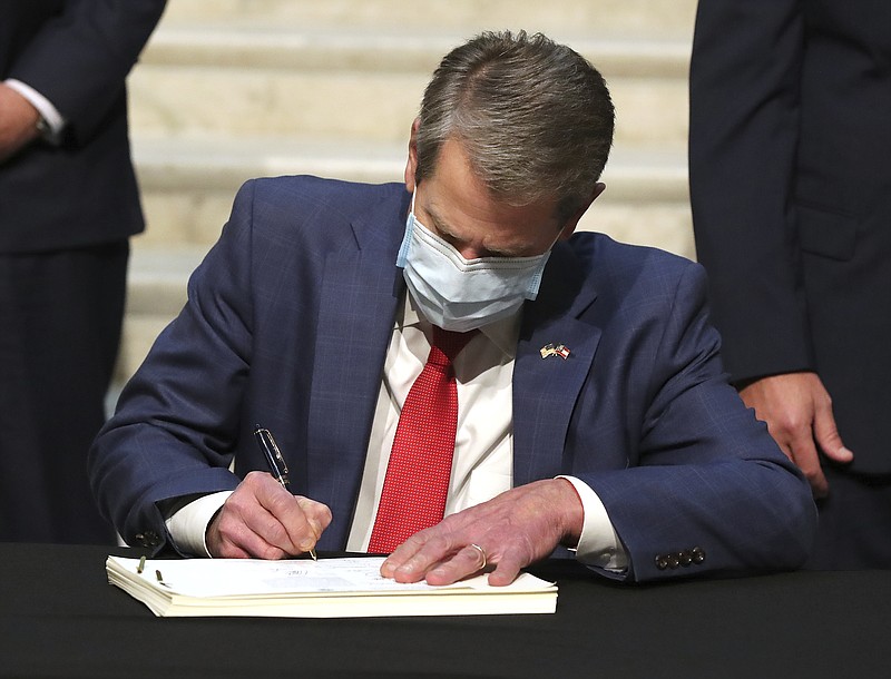 Georgia Governor Brian Kemp signs the amended fiscal year 2021 budget at the capitol in Atlanta, on Monday, Feb 15, 2021. (Curtis Compton/Atlanta Journal-Constitution via AP)