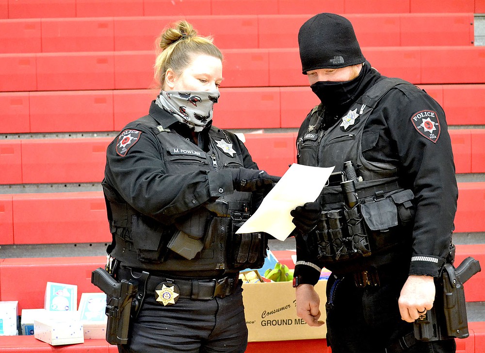 Pea Ridge Police officers Mindy Fowler and Justin Lawson check off a list of supplies for families during the natural gas outage in Pea Ridge Wednesday, Feb. 17, 2021. Supplies gathered for the warming station were delivered to families in need Wednesday by police officers.