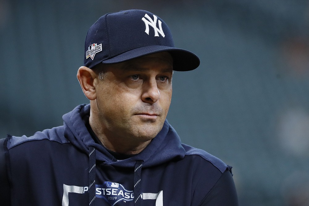 FILE - In this Saturday, Oct. 19, 2019 file photo, New York Yankees manager Aaron Boone watches batting practice before Game 6 of baseball's American League Championship Series against the Houston Astros in Houston. One year later, there's a better understanding of what it takes to play a baseball season amid a pandemic. Pitchers and catchers reported to spring training Wednesday, Feb. 17, 2021. (AP Photo/Matt Slocum, File)