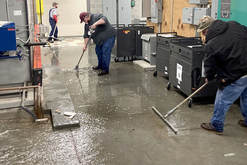Photo submitted
School employees work to squeegee up water in the Siloam Springs High School on Monday.