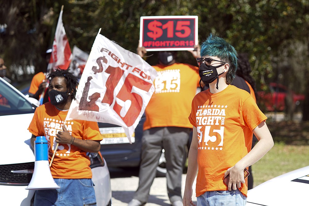 Cristian Cardona, right, an employee at a McDonald's, attends a rally for a $15 an hour minimum wage Tuesday, Feb. 16, 2021, in Orlando, Fla. (AP Photo/John Raoux)