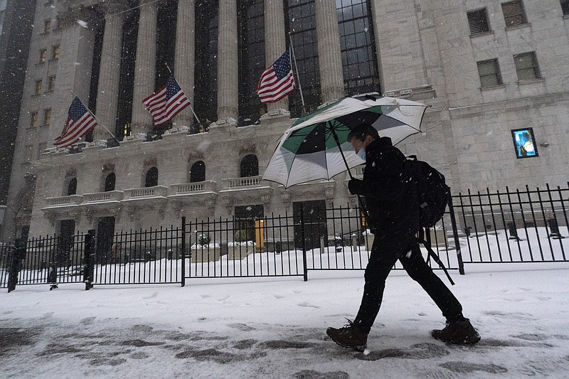 FILE - A man walks past the New York Stock Exchange during a snowstorm, Monday, Feb. 1, 2021, in New York.  Stocks are opening broadly lower on Wall Street and Treasury yields continued to climb. The S&P 500 index gave up 0.8% in the first few minutes of trading Thursday, Feb. 18,  and the tech-heavy Nasdaq was down slightly more, 1.1%. (AP Photo/Mark Lennihan, File)