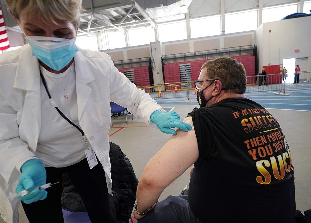 In this Thursday, Feb. 4, 2021 photo, licensed practical nurse Sandra Reeve, left, holds an alcohol swab on the arm of grocery worker Joseph Lupo after administering the first dose of a COVID-19 vaccination to Lupo at an arena on the campus of Suffolk County Community College, Thursday, Feb. 4, 2021, in Brentwood, N.Y. Lupo, a Lidl supervisor who fell ill with the virus in March, was elated to get his first vaccine dose. "I never ever want to get COVID again, or see anybody else get it," said Lupo, 59. (AP Photo/Kathy Willens)