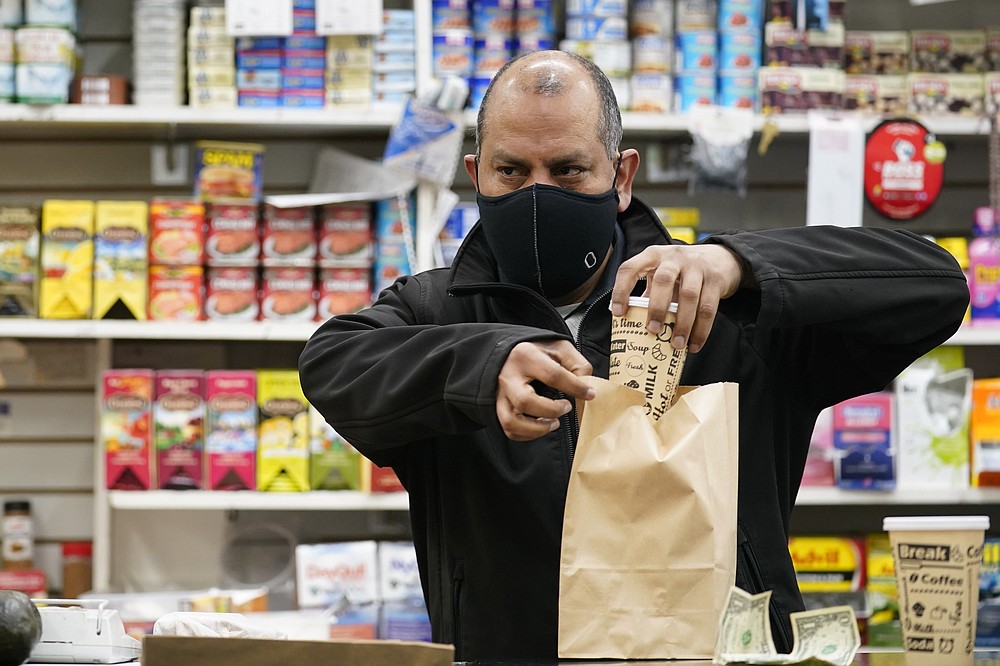 Bodega owner Francisco Marte prepares coffee for a customer, Wednesday, Feb. 10, 2021, at his store in the Bronx borough of New York. Marte, president of the Bodega and Small Business Association of New York, said he has been lobbying local officials to set aside appointments for bodega workers, many of whom are unaware they are eligible. He hopes that the recent opening of a large vaccination site at Yankee stadium will make access easier. (AP Photo/Kathy Willens)