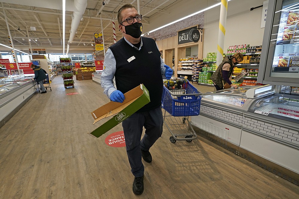 In this Thursday, Feb. 4, 2021 photo, Lidl employee Joseph Lupo makes his rounds tidying up in the Long Island grocery store where he works in Lake Grove, N.Y. Earlier in the day, Lupo received the first dose of the COVID-19 vaccination at a Suffolk County Community College vaccination hub located in a giant arena repurposed for vaccinations. (AP Photo/Kathy Willens)
