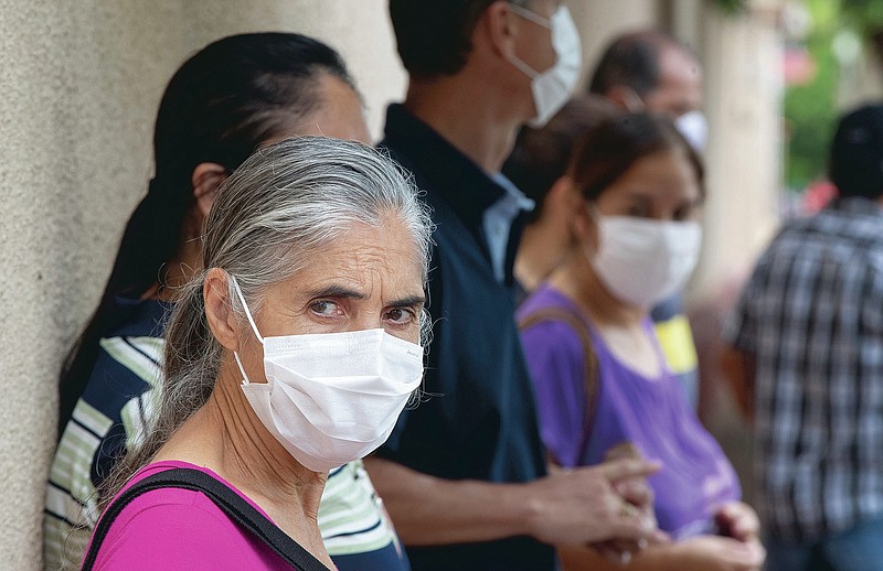 Seventy-year-old Marlene Negrao waits in line outside a public school to get a shot of China's Sinovac CoronaVac vaccine in Serrana, Sao Paulo state, Brazil, Wednesday, Feb. 17, 2021. Brazil's Butantan Institute has started a mass vaccination on Wednesday of the city's entire adult population, about 30,000 people, to test the virus' behaviour in response to the vaccine. (AP Photo/Andre Penner)