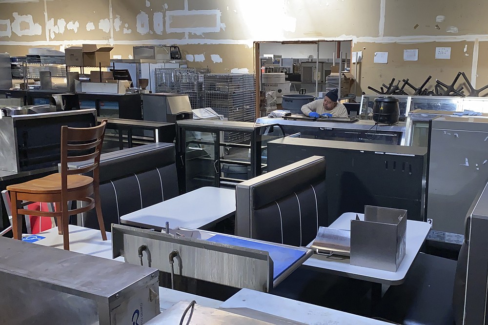 An employee cleans used equipment for sale inside the warehouse of American Restaurant Supply, which is packed with appliances and furniture from restaurants that have shut down during the pandemic, in San Leandro, Calif., on Jan. 14, 2021. The pandemic has forced thousands of restaurants to permanently shut their doors as dining restrictions keep customers away. But the unprecedented closures have created a business boom for commercial auctioneers that buy and sell used restaurant equipment. (AP Photo/Terry Chea)
