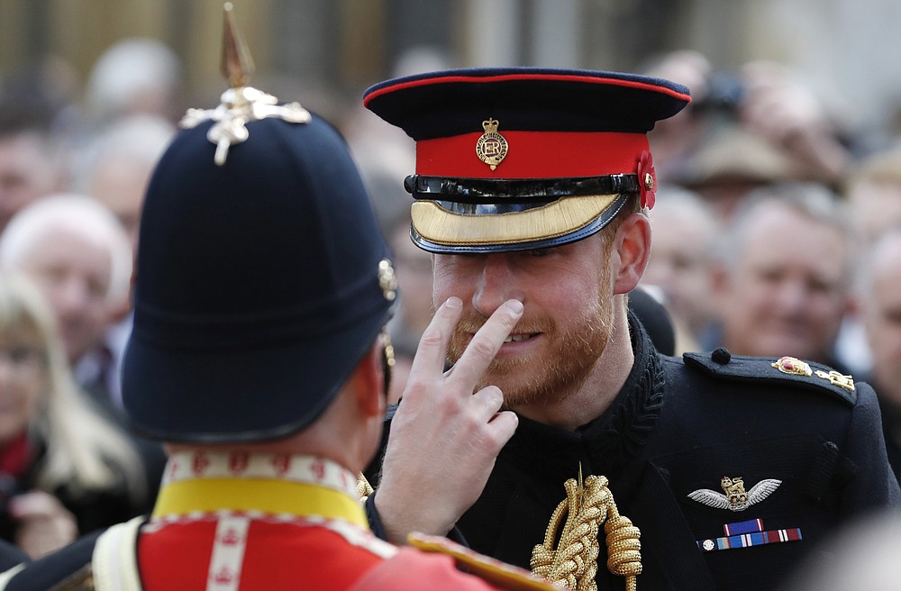 FILE - In this Nov. 8, 2018 file photo Britain's Prince Harry gestures to a serviceman as he attends the annual Field of Remembrance service at Westminster Abbey in London. Harry and Meghan stepped away from full-time royal life in early 2020, and Buckingham Palace on Friday Feb. 19, 2021, confirmed the couple will not be returning to royal duties, and Harry will give up his honorary military titles. (AP Photo/Alastair Grant, File)