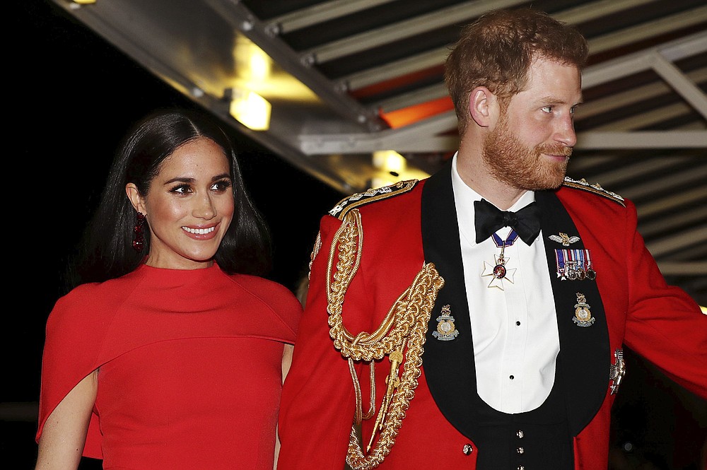 FILE - In this Saturday March 7, 2020 file photo, Britain's Prince Harry and Meghan, Duchess of Sussex arrive at the Royal Albert Hall in London, to attend the Mountbatten Festival of Music. Harry and Meghan stepped away from full-time royal life in early 2020, and Buckingham Palace on Friday Feb. 19, 2021, confirmed the couple will not be returning to royal duties, and Harry will give up his honorary military titles. (Simon Dawson/Pool via AP, file)