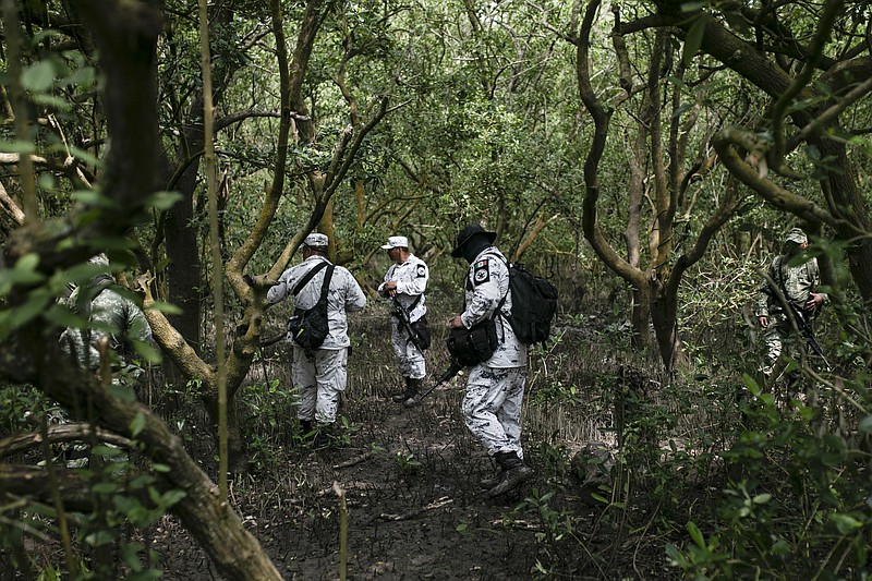 Soldiers of the Mexican Army and members of the National Guard search for possible clandestine gravesites in Puquita a tropical mangrove island, near Alvarado in the Gulf coast state of Veracruz, Mexico, Thursday, Feb. 18, 2021. Investigators from the National Search Commission found three pits with human remains and plastic bags inside. The number of bodies there has not yet been determined. (AP Photo/Felix Marquez)