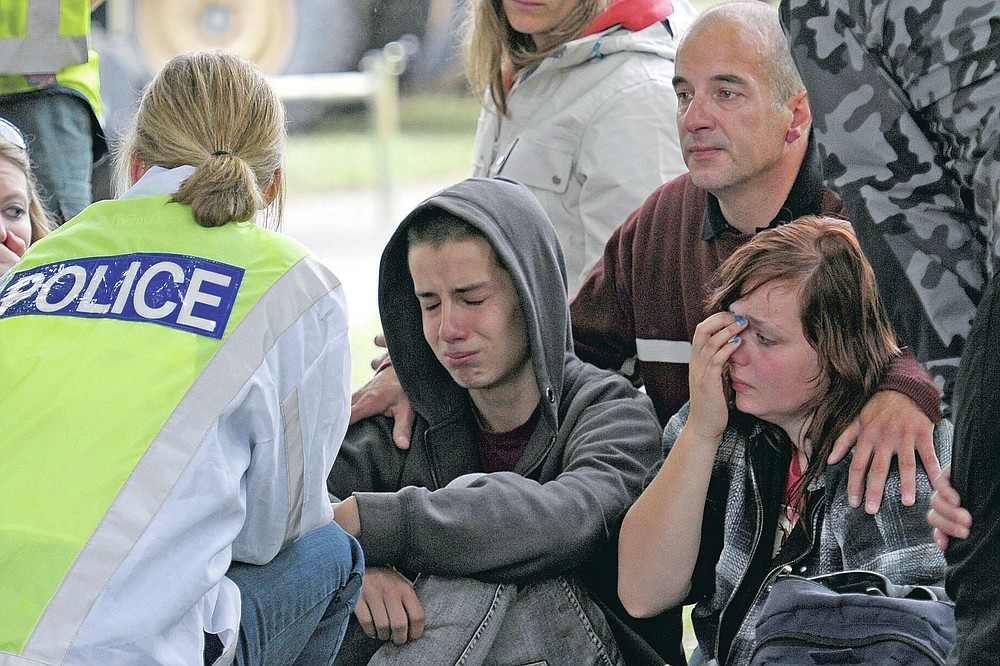 FILE - In this Feb 23, 2011, file photo, police inform Kent Manning, 15, second from left, Lizzy Manning, 18, right, and their father Jonathan Manning, there is no chance of survivors in the CTV building in Christchurch, New Zealand, after the city was hit by a 6.3 earthquake on Feb 22, 2011. One woman has used her anger to ensure buildings are safer. Others have found peace after heartbreaking losses. Ten years after an earthquake in Christchurch killed 185 people and devastated the city, some of those profoundly affected are sharing their journeys. (AP Photo/Rob Griffith, File)