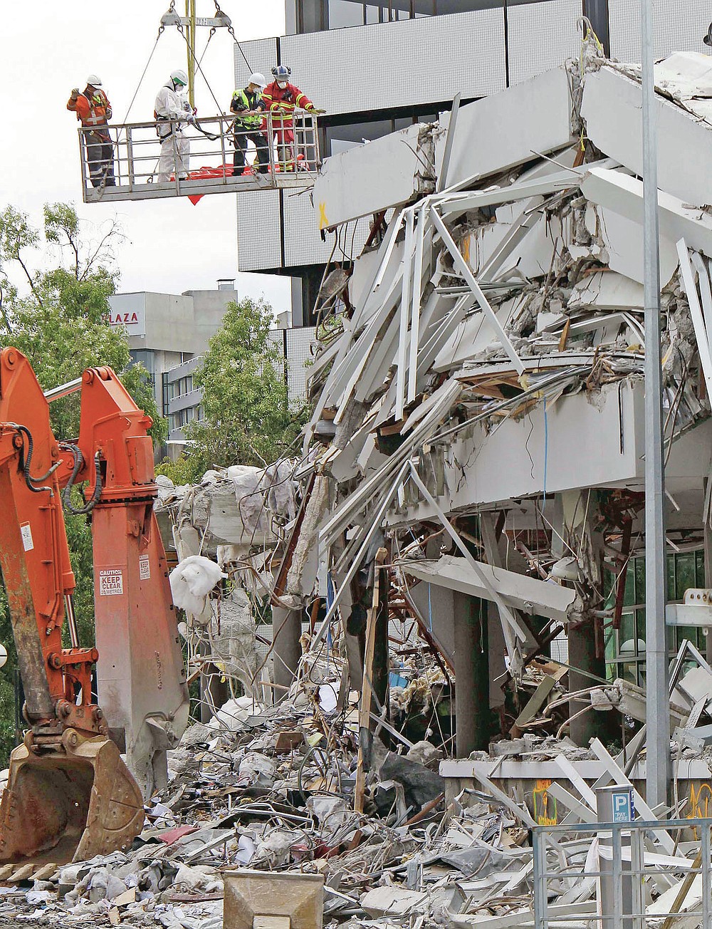 FILE - In this Feb. 26, 2011, file photo, recovery workers inspect the earthquake-damaged Pyne Gould Corporation building in Christchurch, New Zealand. One woman has used her anger to ensure buildings are safer. Others have found peace after heartbreaking losses. Ten years after an earthquake in Christchurch killed 185 people and devastated the city, some of those profoundly affected are sharing their journeys. (AP Photo/Mark Baker, File)