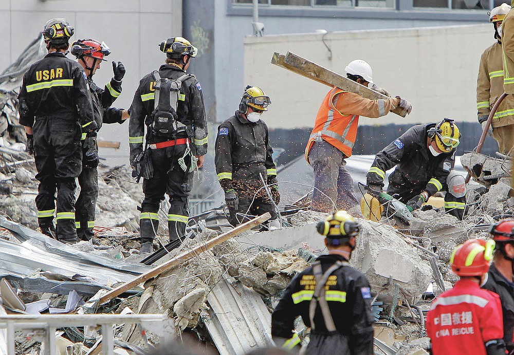FILE- In this Feb. 26, 2011, file photo, recovery workers sift through the rubble of the earthquake-damaged CTV building in Christchurch, New Zealand. One woman has used her anger to ensure buildings are safer. Others have found peace after heartbreaking losses. Ten years after the earthquake in Christchurch killed 185 people and devastated the city, some of those profoundly affected are sharing their journeys.(AP Photo/Mark Baker, File)