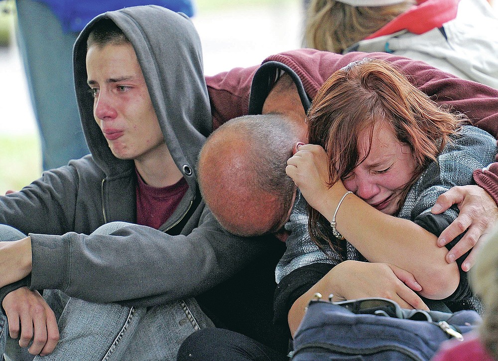 FILE - In this Feb 23, 2011, file photo, police inform Kent Manning, 15, left, Lizzy Manning, 18, right, and their father Jonathan, center, there is no chance of survivors in the CTV building in Christchurch, New Zealand, after the city was hit by a 6.3 earthquake on Feb 22, 2011. One woman has used her anger to ensure buildings are safer. Others have found peace after heartbreaking losses. Ten years after the earthquake in Christchurch killed 185 people and devastated the city, some of those profoundly affected are sharing their journeys. (AP Photo/Rob Griffith, File)