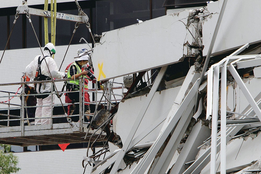 FILE - In this Feb. 26, 2011, file photo, recovery workers inspect the earthquake-damaged Pyne Gould Corporation building in Christchurch, New Zealand. One woman has used her anger to ensure buildings are safer. Others have found peace after heartbreaking losses. Ten years after the earthquake in Christchurch killed 185 people and devastated the city, some of those profoundly affected are sharing their journeys.(AP Photo/Mark Baker, File)