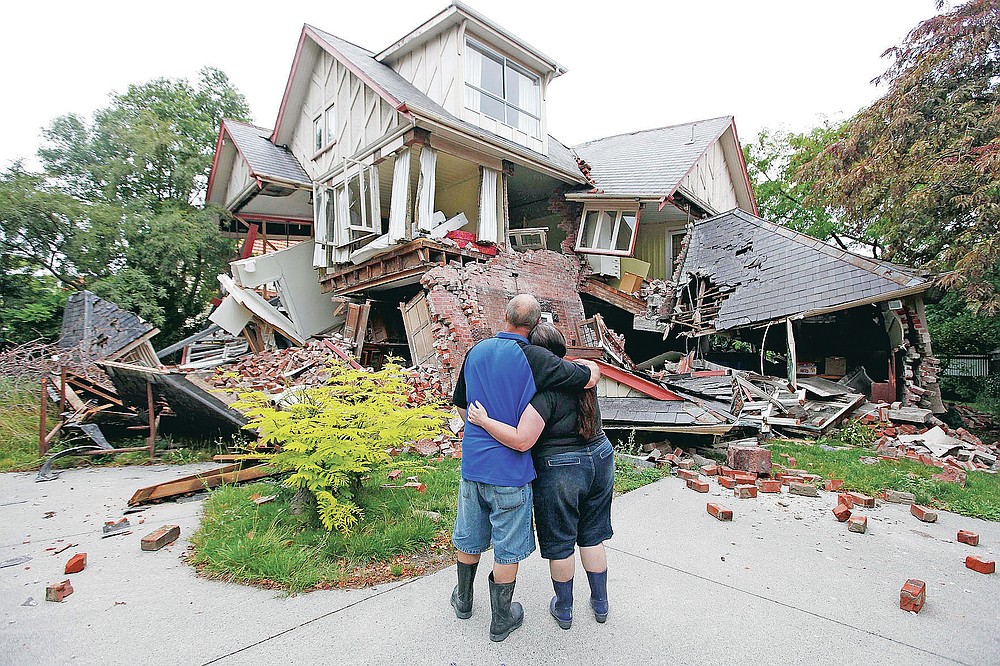 FILE - In this Feb. 23, 2011, file photo, Murray James, left, and Kelly James look at their destroyed house in central Christchurch, New Zealand, a day after a deadly earthquake. One woman has used her anger to ensure buildings are safer. Others have found peace after heartbreaking losses. Ten years after the earthquake in Christchurch killed 185 people and devastated the city, some of those profoundly affected are sharing their journeys. (AP Photo/Mark Baker, File)