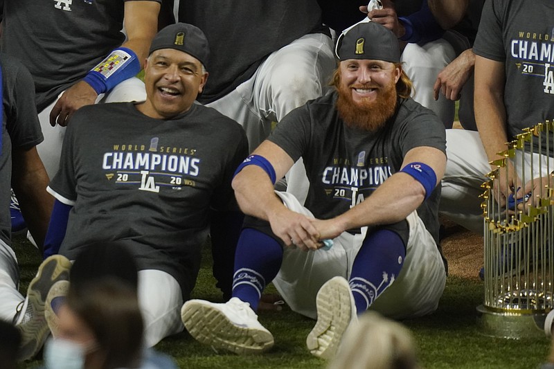 FILE - Los Angeles Dodgers manager Dave Roberts, left, and third baseman Justin Turner pose for a group picture after the Dodgers defeated the Tampa Bay Rays 3-1 in Game 6 to win the baseball World Series in Arlington, Texas, in this Tuesday, Oct. 27, 2020, file photo. Justin Turner's extended flirtation with free agency ended where it began — with the Los Angeles Dodgers. Along the way, the third baseman had doubts about whether he would return to his hometown team and wondered if his mask-less appearance on the field to celebrate its World Series championship would hurt him. (AP Photo/Eric Gay, File)