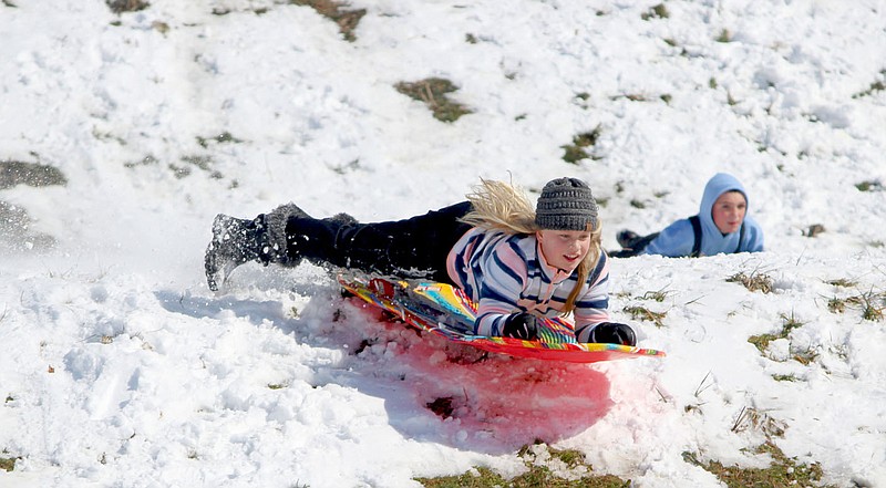 Keith Bryant/The Weekly Vista
Harper Phillips, 9, catches a small bit of air as she sleds down the Lake Ann dam with Beyor Bohannon, 9, a short distance behind.