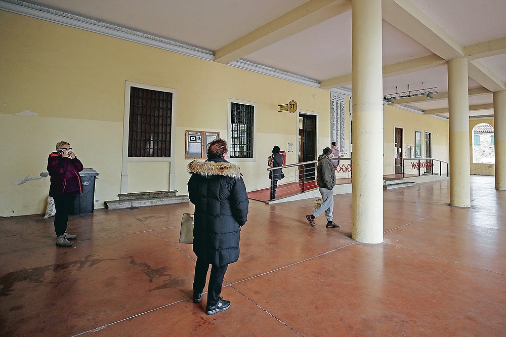 People queue at the post office in Vo Euganeo, Italy, Wednesday, Feb. 10, 2021. Shockwaves ran through the wine-making village of Vo, west of Venice, as word spread last Feb. 21 that a retired roofer had died of the new coronavirus becoming the first known COVID-19 victim in the West. (AP Photo/Luca Bruno)