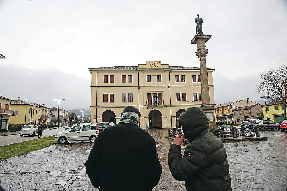 People walk in front of the Vo Euganeo town hall, in Vo' Euganeo, northern Italy, Wednesday, Feb. 10, 2021. Shockwaves ran through the wine-making village of Vo, west of Venice, as word spread last Feb. 21 that a retired roofer had died of the new coronavirus becoming the first known COVID-19 victim in the West. (AP Photo/Luca Bruno)