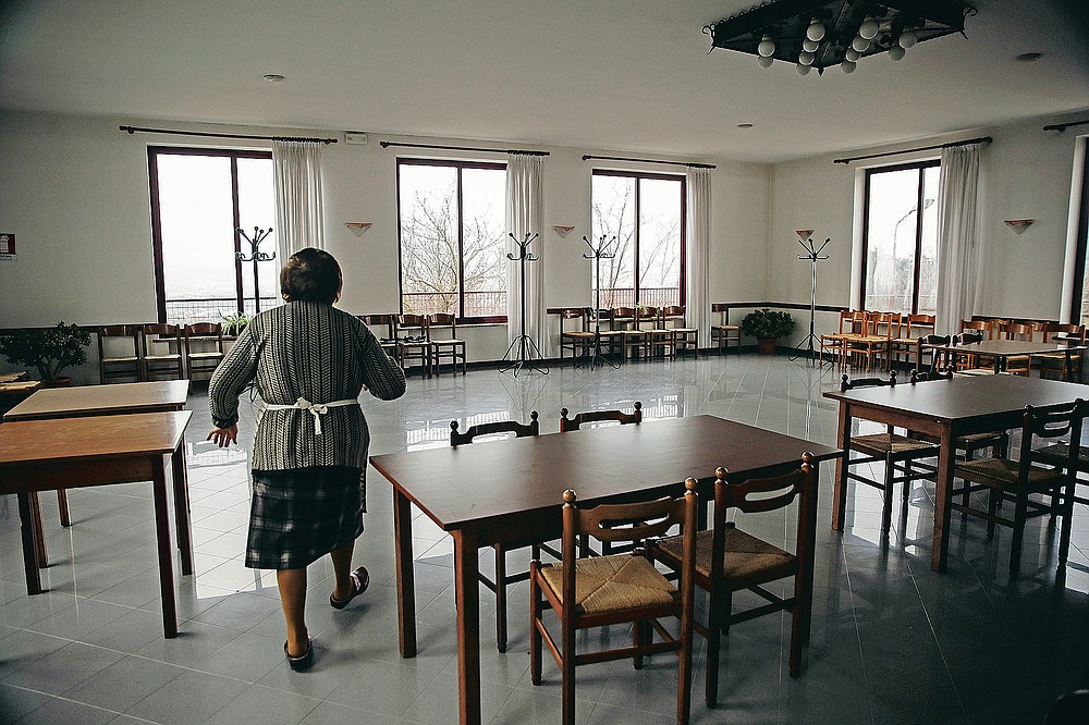 The owner of a restaurant walks through the dining room, in Vo Euganeo, northern Italy, Wednesday, Feb. 10, 2021. Shockwaves ran through the wine-making village of Vo', west of Venice, as word spread last Feb. 21 that a retired roofer had died of the new coronavirus becoming the first known COVID-19 victim in the West. (AP Photo/Luca Bruno)
