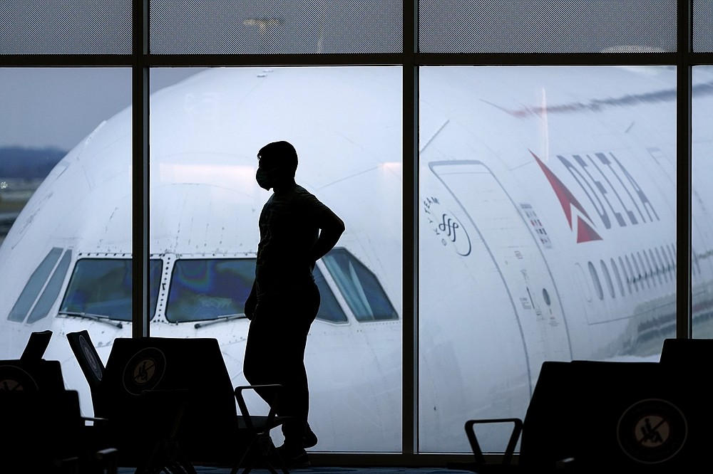 FILE - In this Feb. 18, 2021, file photo, a passenger wears a face mask to help prevent against the spread of the coronavirus as he waits for a Delta Airlines flight at Hartsfield-Jackson International Airport in Atlanta. At least for now, U.S. health authorities say after being vaccinated, people should follow the same rules as everybody else about wearing a mask, keeping a 6-foot distance and avoiding crowds even after they’ve gotten their second vaccine dose. (AP Photo/Charlie Riedel, File)