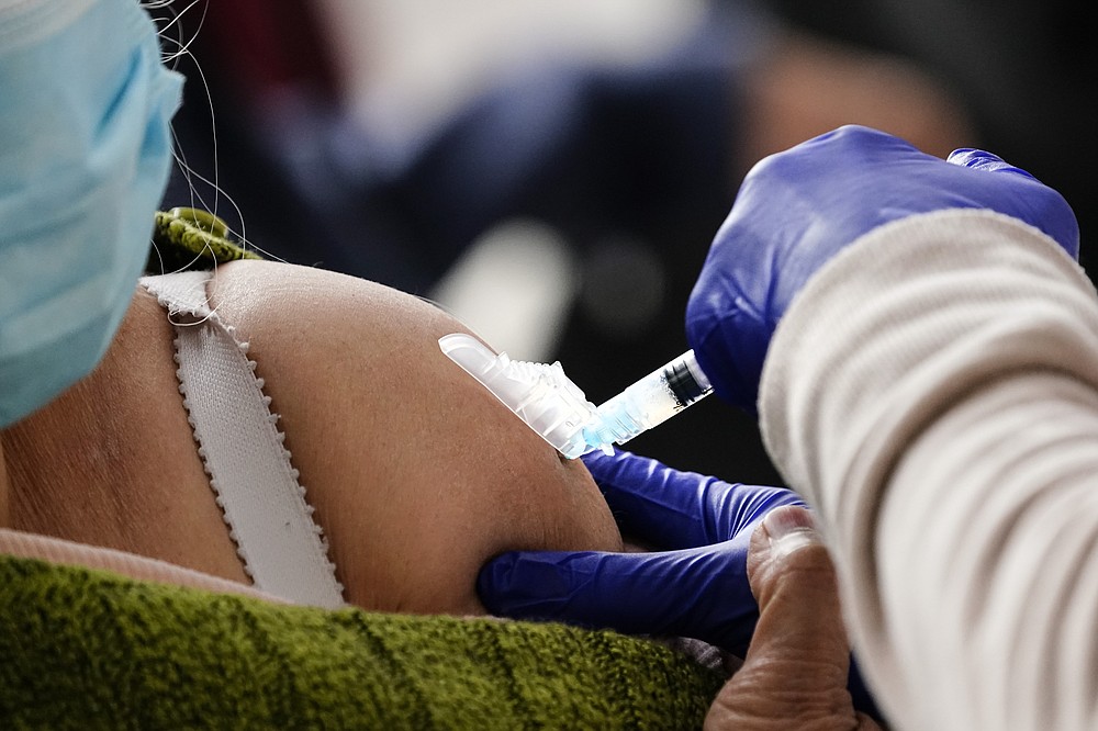 FILE - In this Feb. 19, 2021, file photo, a person receives a COVID-19 vaccinations at a 24-hour, walk-up clinic hosted by the Black Doctors COVID-19 Consortium at Temple University's Liacouras Center in Philadelphia. At least for now, U.S. health authorities say after being vaccinated, people should follow the same rules as everybody else about wearing a mask, keeping a 6-foot distance and avoiding crowds even after they’ve gotten their second vaccine dose. (AP Photo/Matt Rourke, File)
