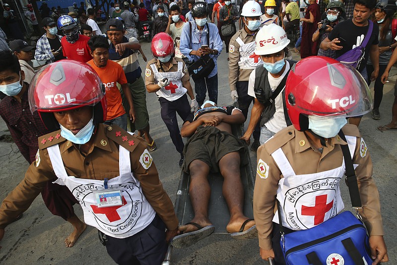 Red Cross workers carry a man on a stretcher in Mandalay, Myanmar on Saturday, Feb. 20, 2021. Security forces in Myanmar ratcheted up their pressure against anti-coup protesters Saturday, using water cannons, tear gas, slingshots and rubber bullets against demonstrators and striking dock workers in Mandalay, the nation's second-largest city. (AP Photos)