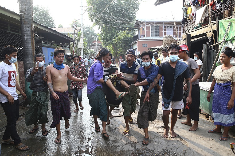 A man is carried after police dispersed protesters in Mandalay, Myanmar on Saturday, Feb. 20, 2021. Security forces in Myanmar ratcheted up their pressure against anti-coup protesters Saturday, using water cannons, tear gas, slingshots and rubber bullets against demonstrators and striking dock workers in Mandalay, the nation's second-largest city. (AP Photos)