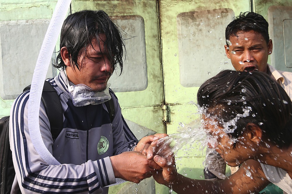 People rinse their faces with water after tear gas was used to disperse a protest in Mandalay, Myanmar on Saturday, Feb. 20, 2021.Security forces in Myanmar ratcheted up their pressure against anti-coup protesters Saturday, using water cannons, tear gas, slingshots and rubber bullets against demonstrators and striking dock workers in Mandalay, the nation's second-largest city. (AP Photos)